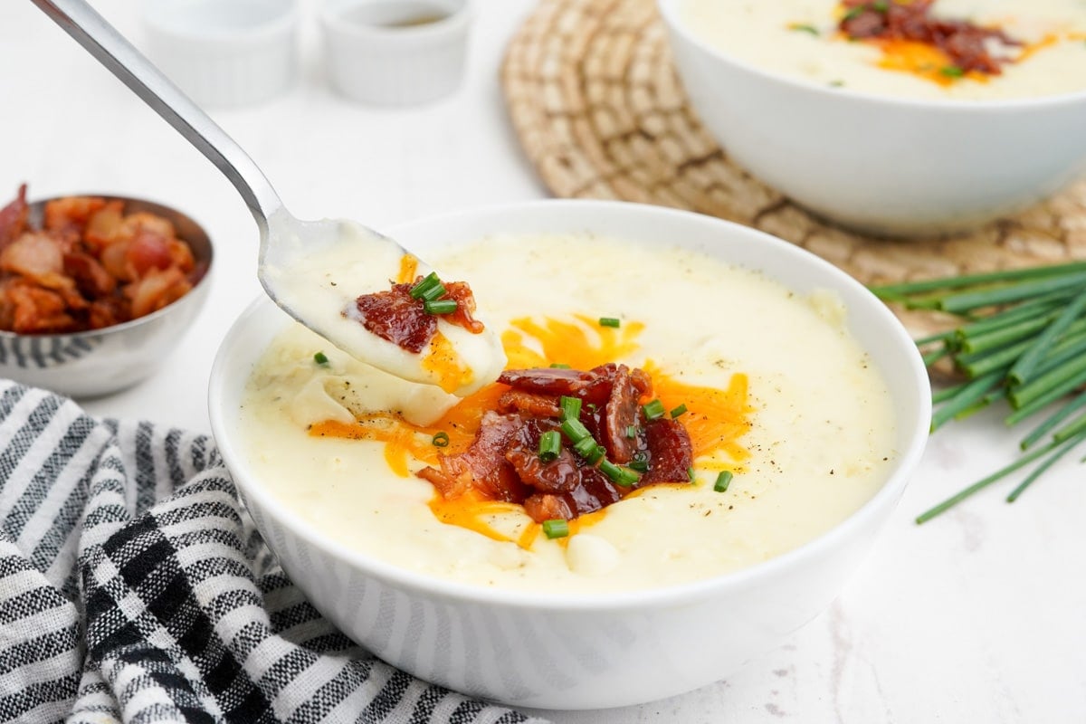 Bowl of potato soup topped with bacon, cheese and chives.