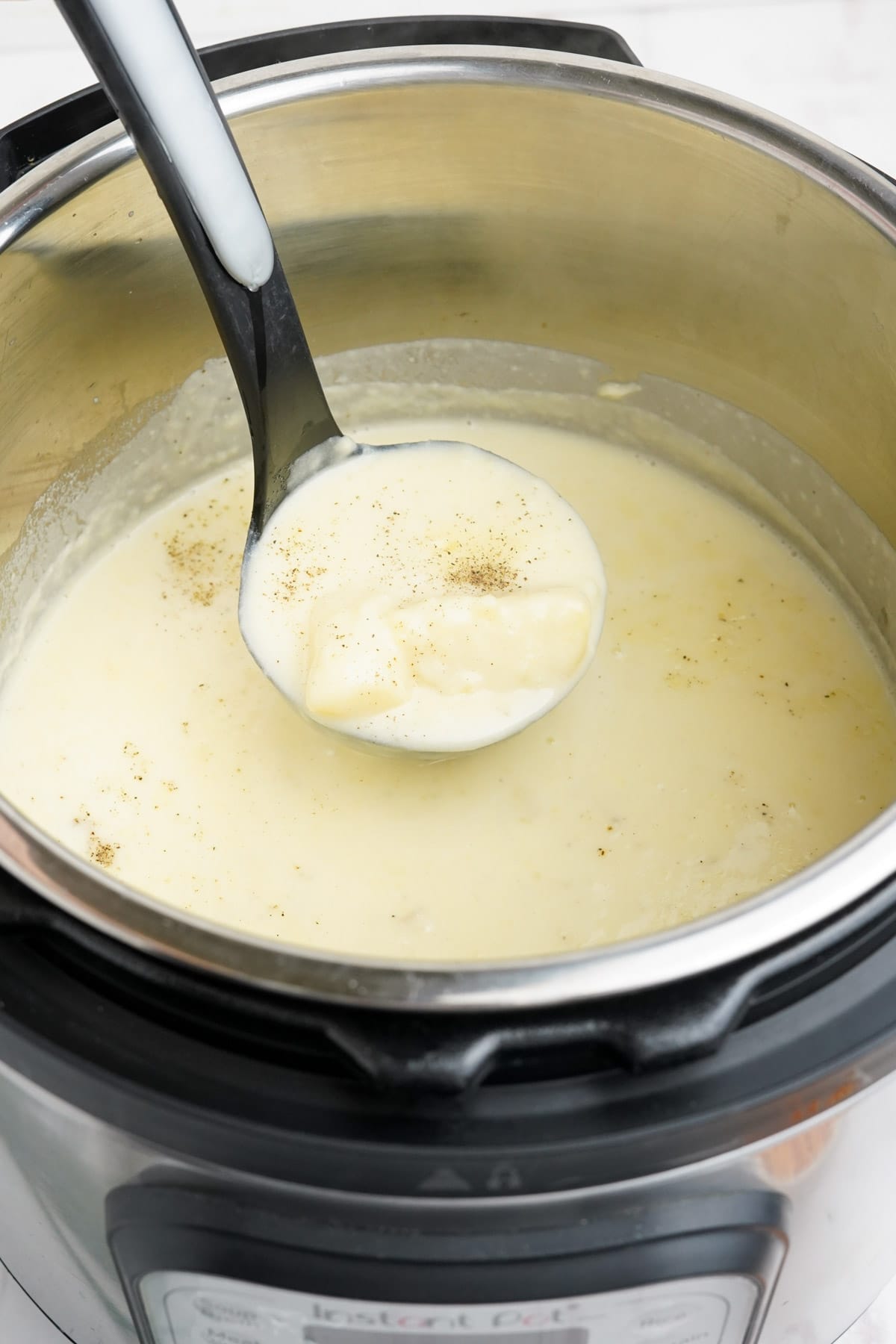 Potato soup in an instant pot with a ladle of soup in focus.