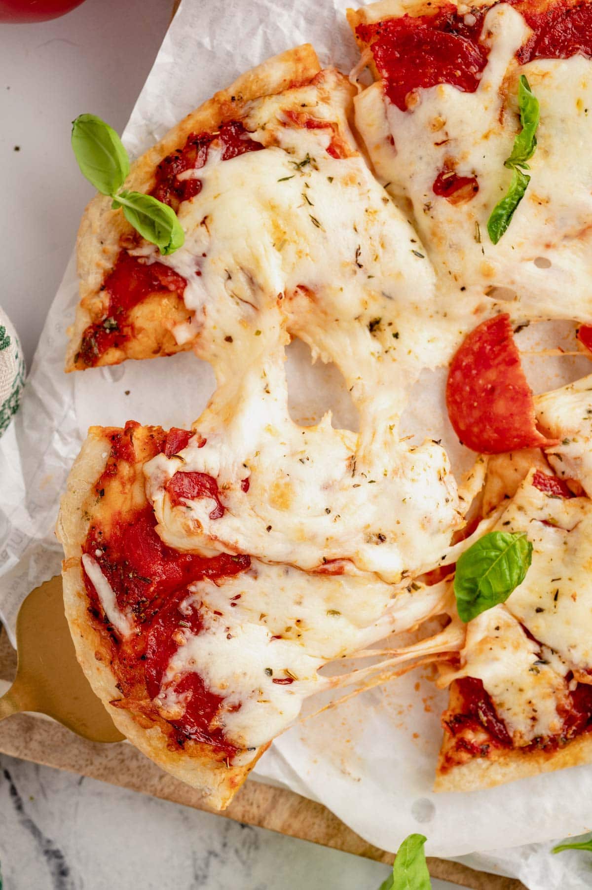 Pizza on a parchment paper with slices pulled out.