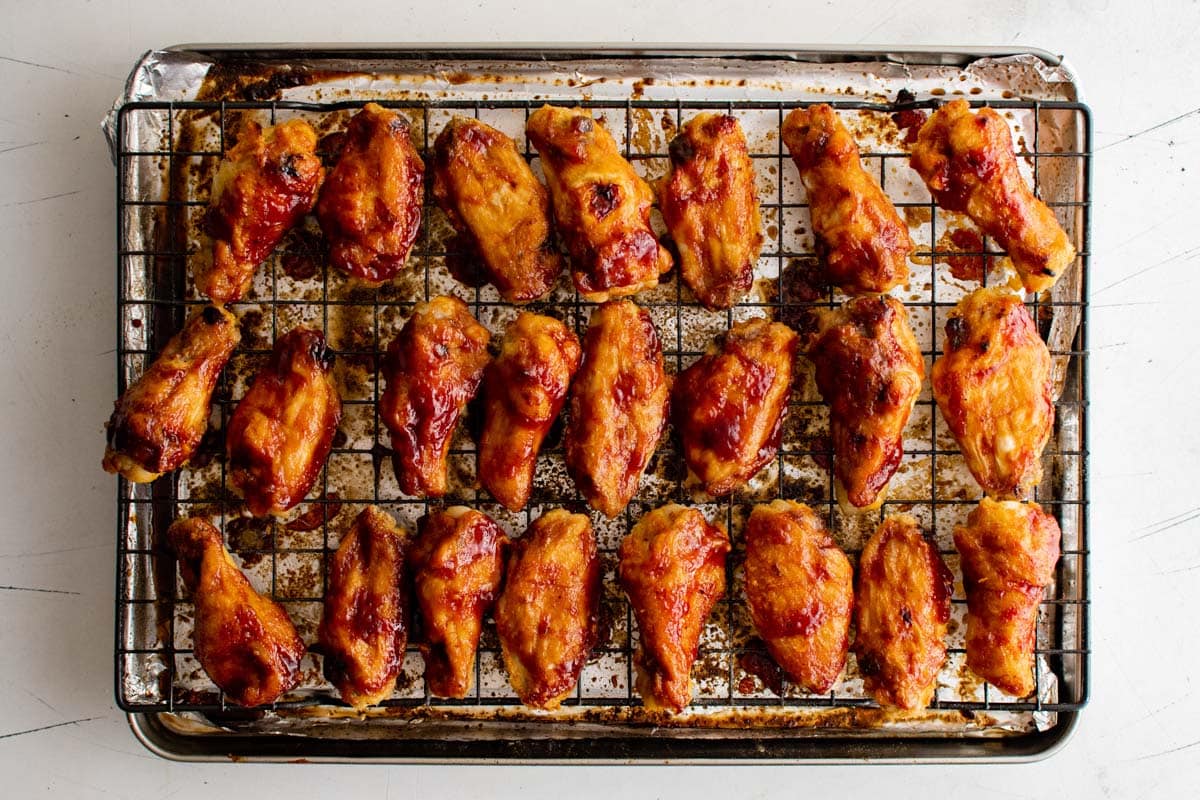 BBW sauced chicken wings on a baking rack and baking sheet.