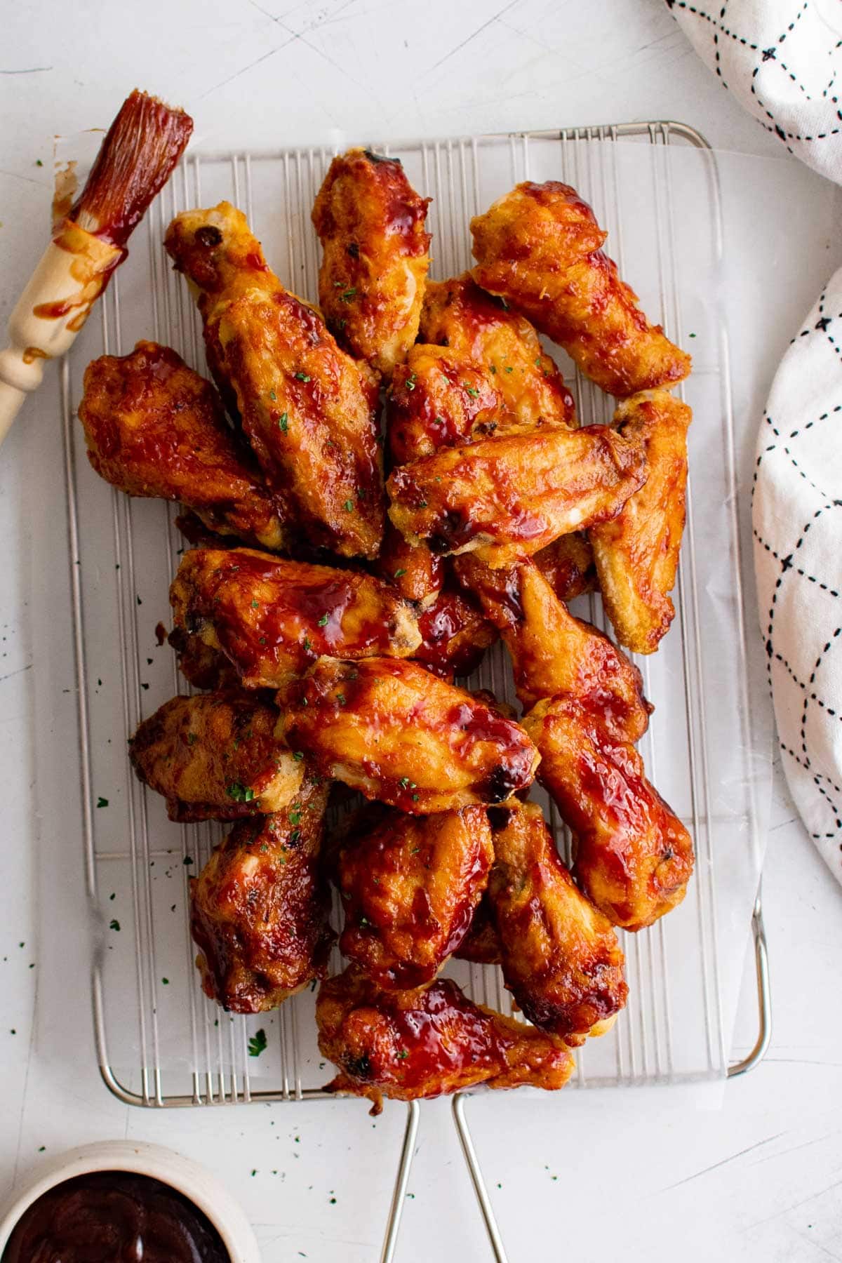 BBQ sauced chicken wings in a pile on a white platter.