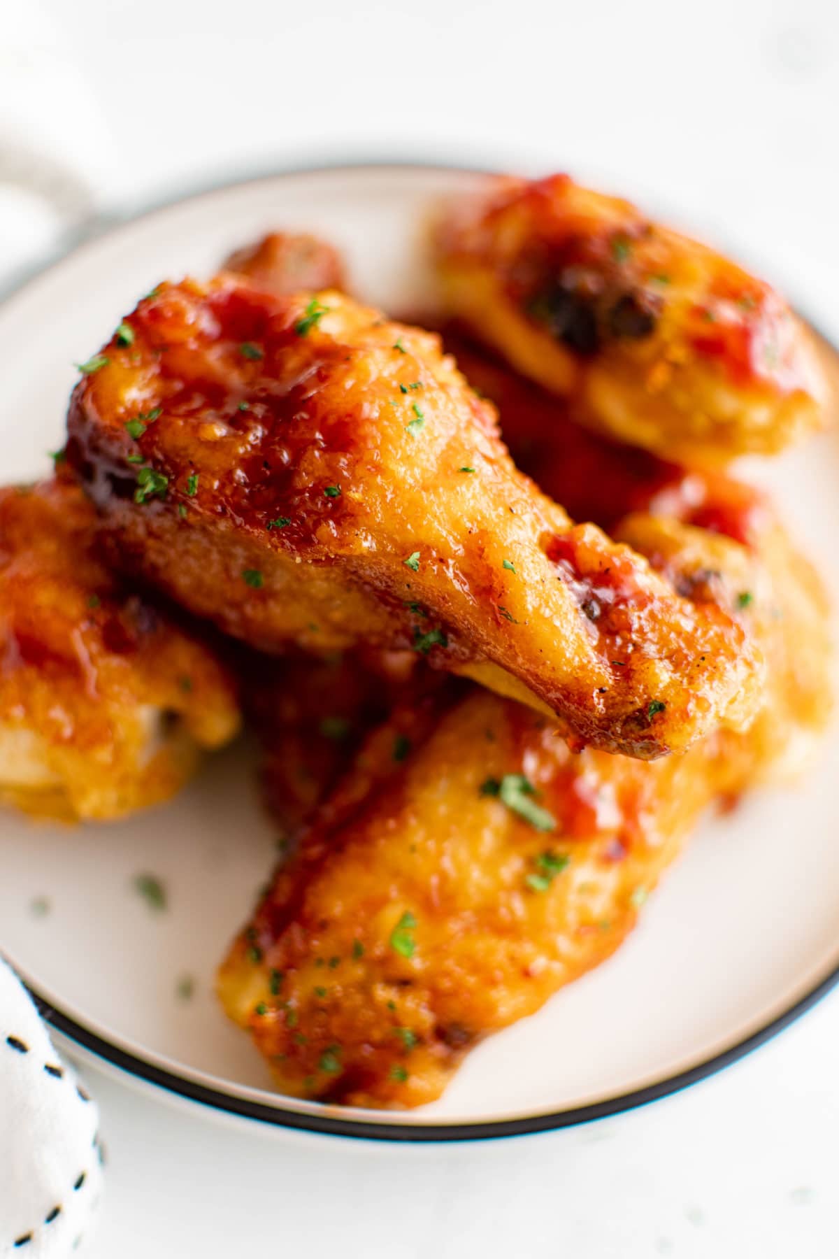 A few chicken wings with bbq sauce on a plate.