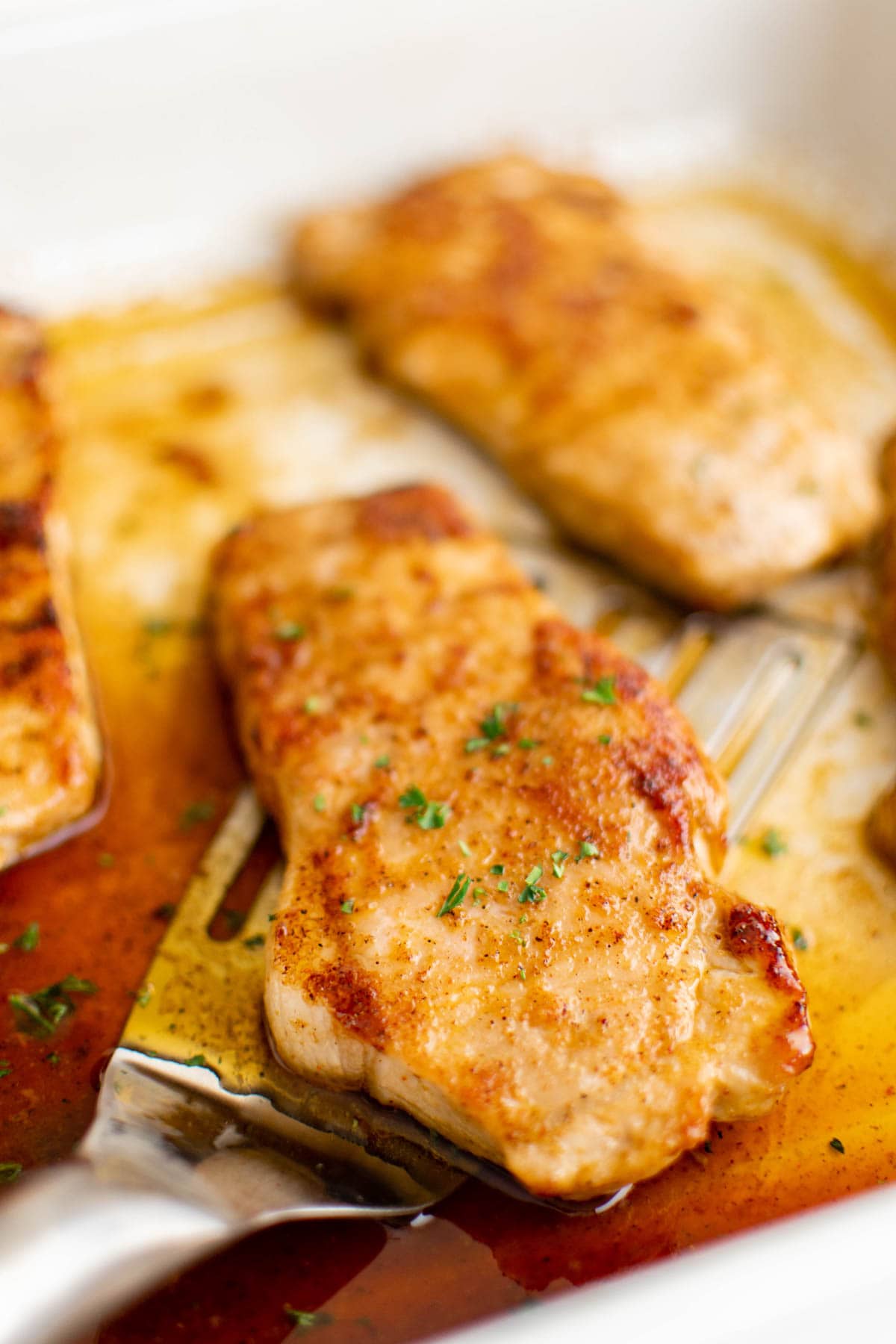 A pork chop, golden in color and juicy, held on a spatula.