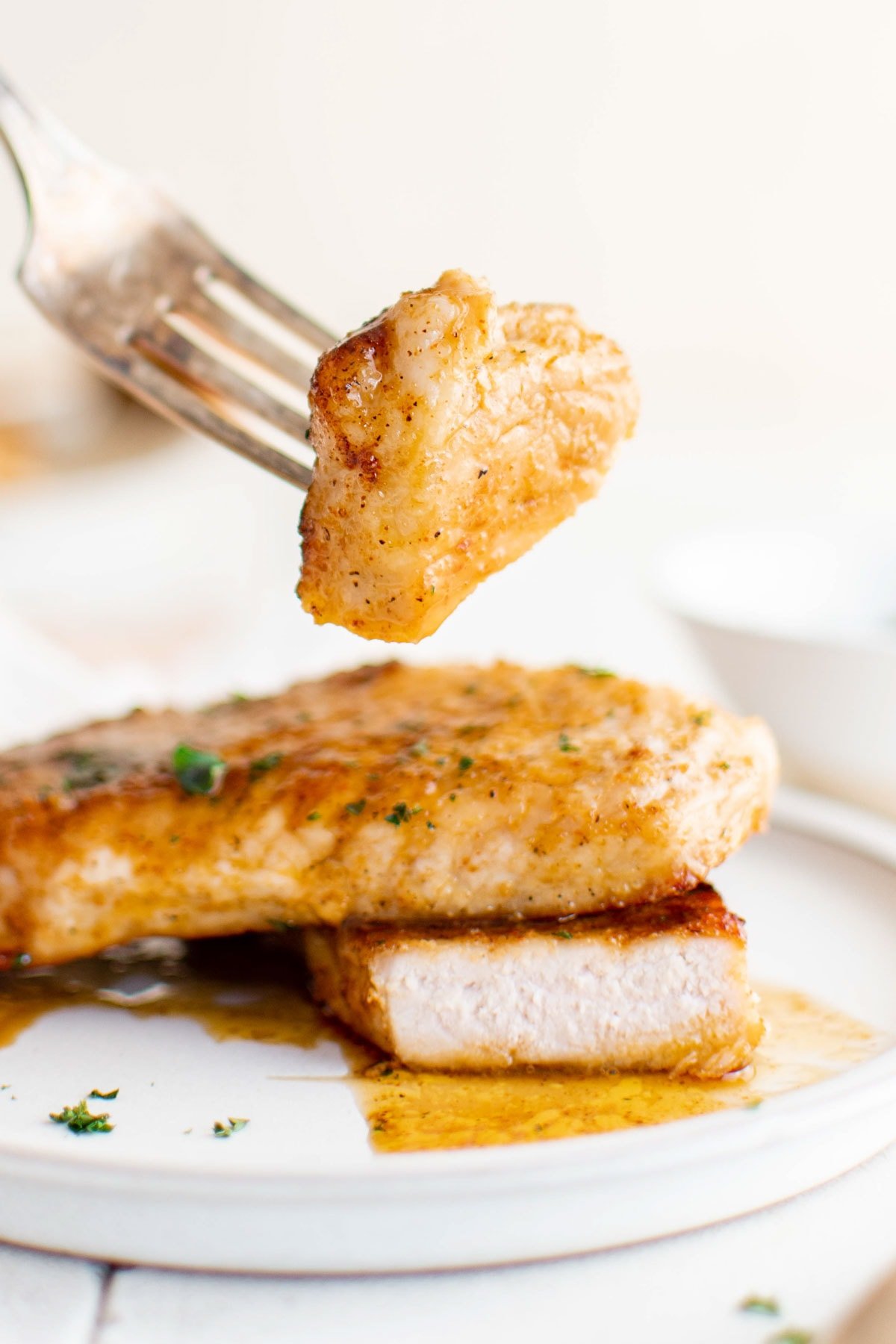 Easy Baked Pork Chops are so tender and juicy, and the brown sugar spice rub gives this boneless pork chops a ton of flavor! | How to bake pork chops for dinner. A pork chop, a slice taken out with a fork.