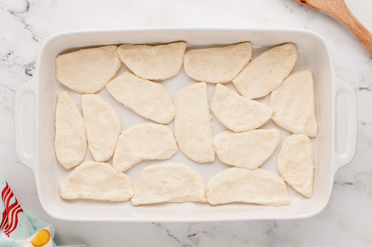 Cut up refrigerated biscuits in a baking dish.