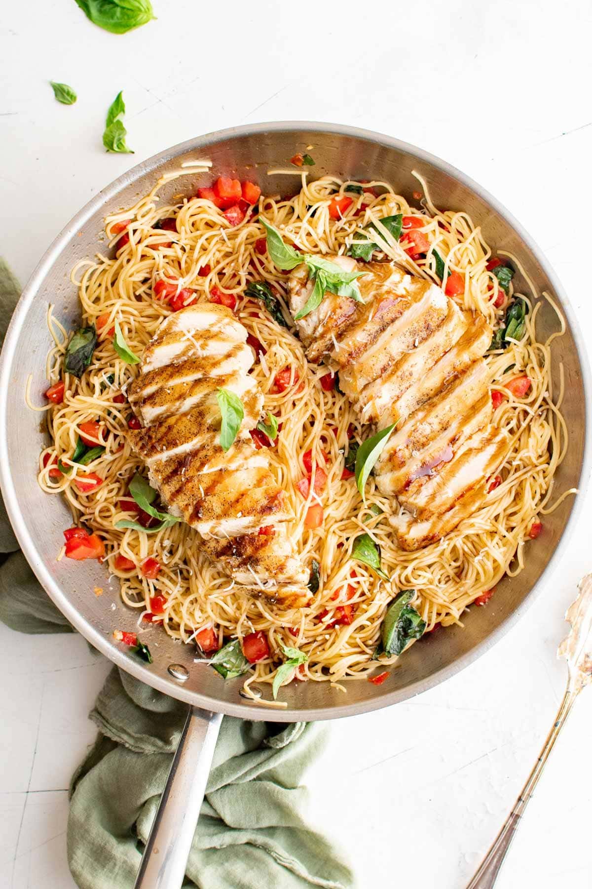Sliced chicken breast over pasta with tomatoes with balsamic glaze.