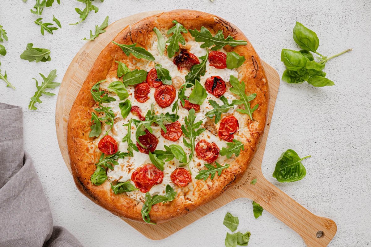 Baked pizza with cheese and tomatoes, fresh basil and arugula.