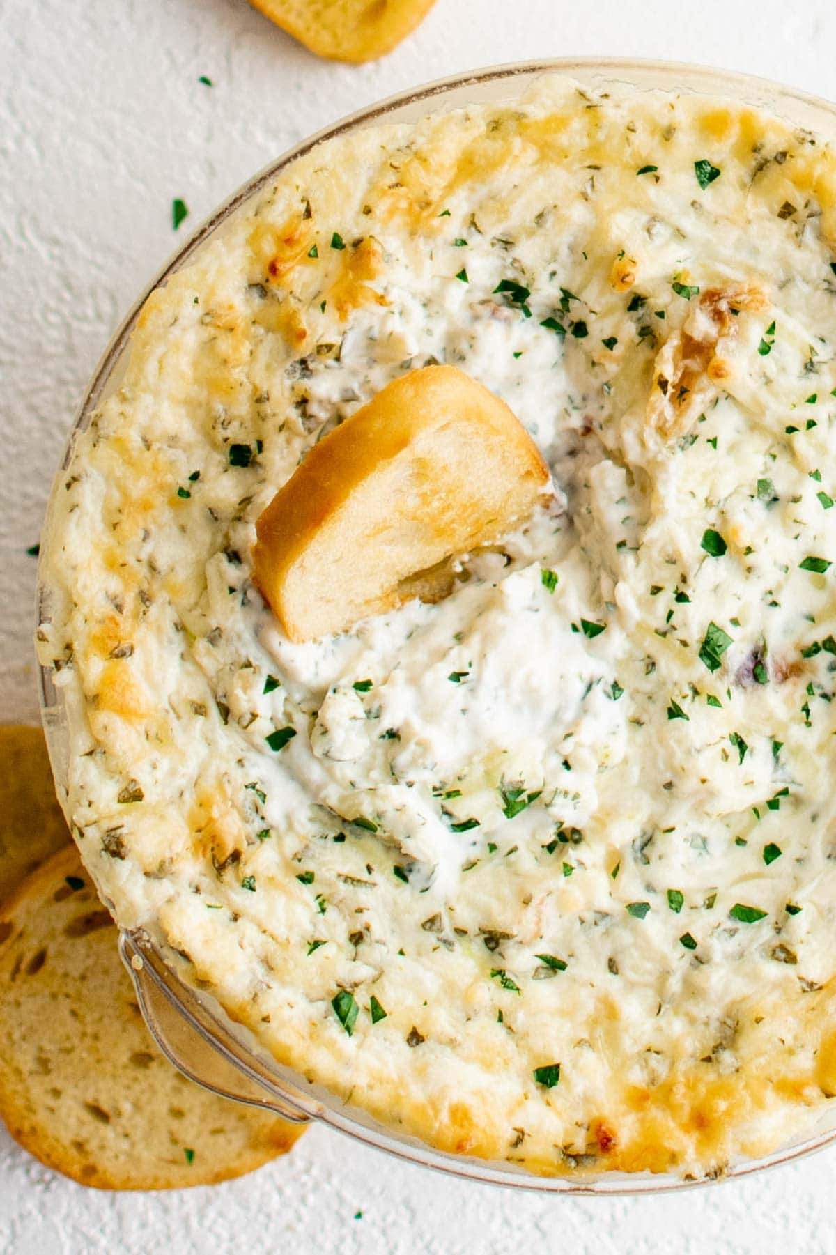 Roasted Garlic Dip in a baking dish with a piece of crostini.