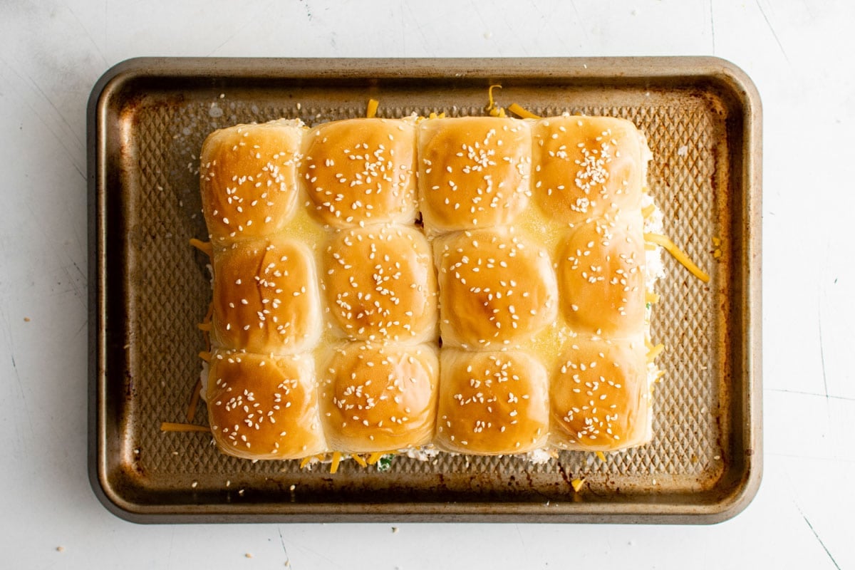 Hawaiian dinner rolls with melted butter and sesame seeds on top.