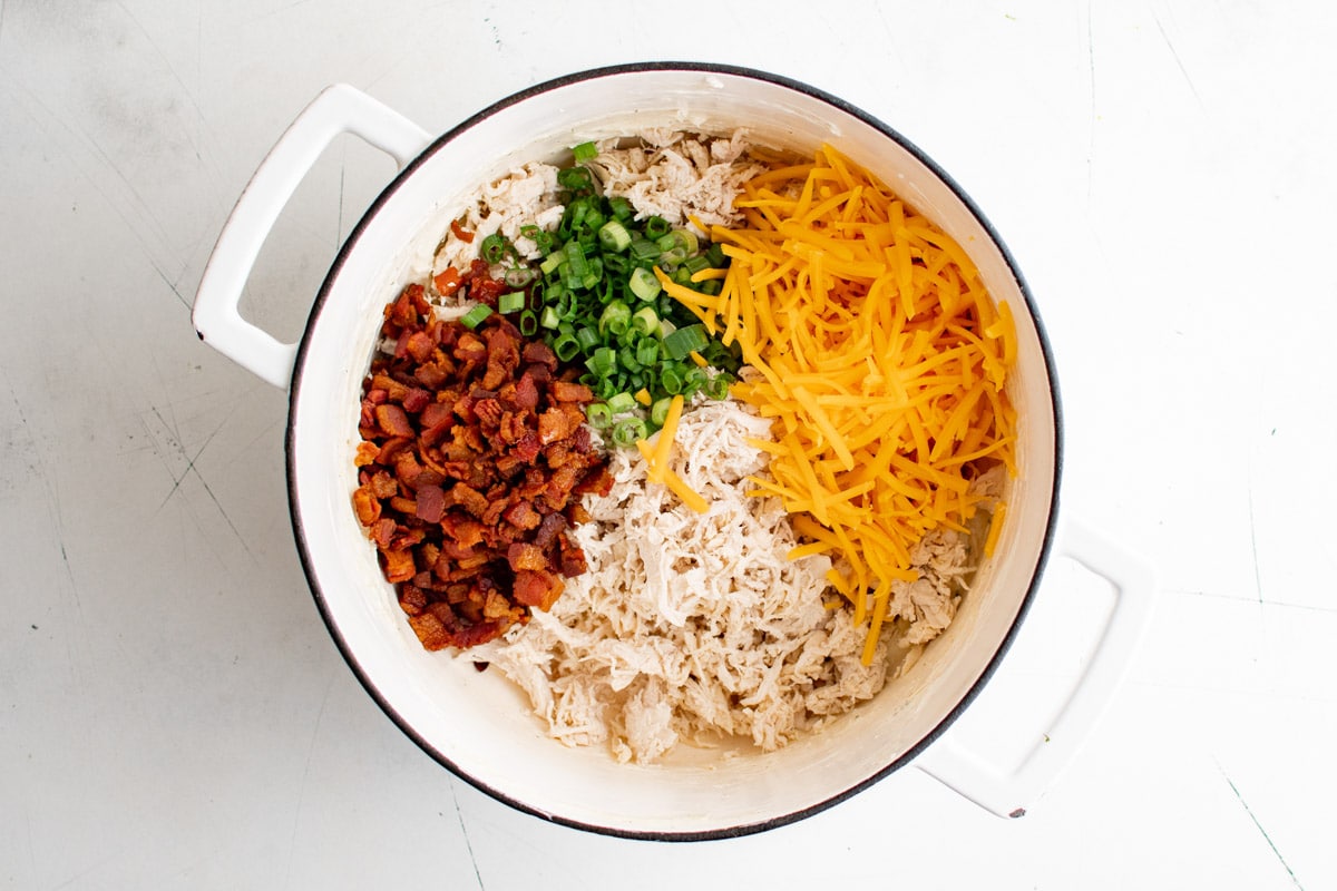 Chopped bacon, diced green onions, shredded chicken, shredded cheese in a large pot.