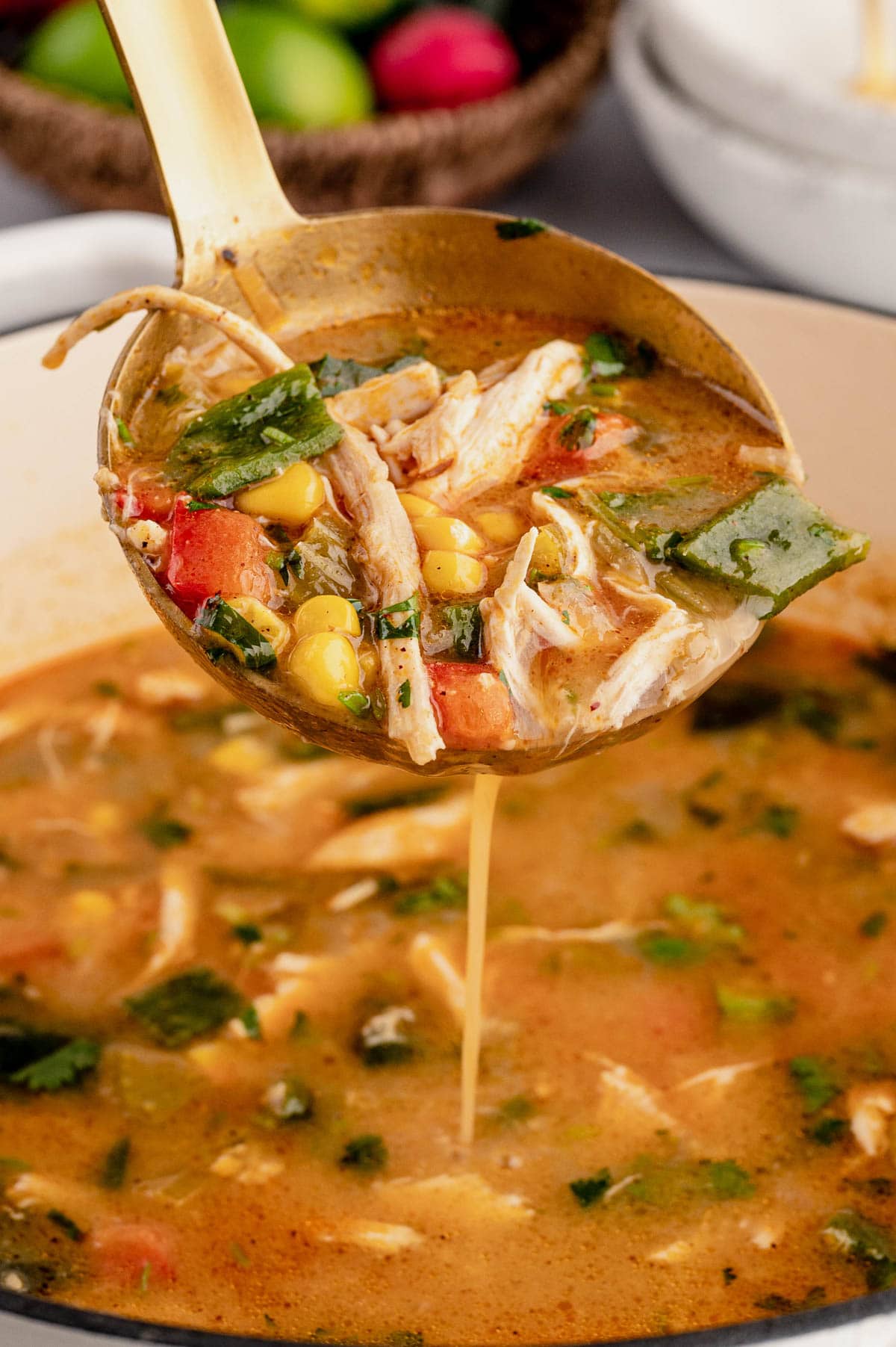 Chicken Poblano Soup in a ladle over a pot of soup.