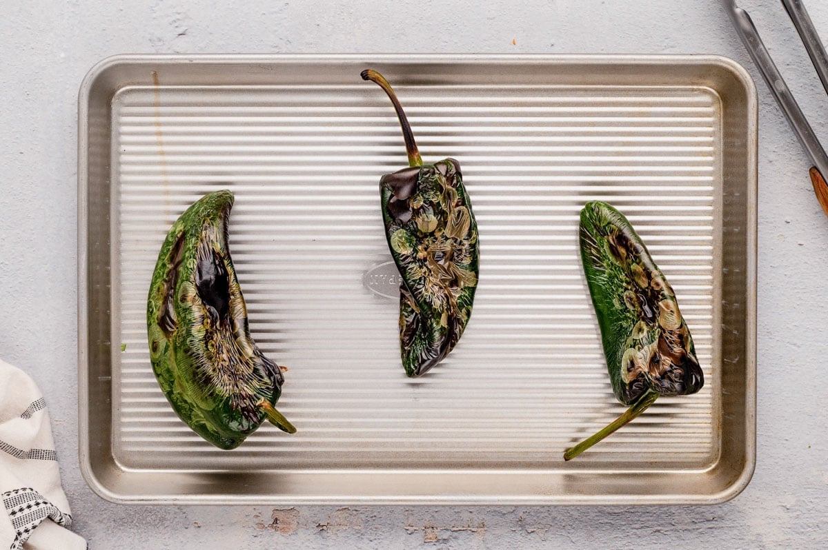 Charred poblano peppers on a baking sheet.