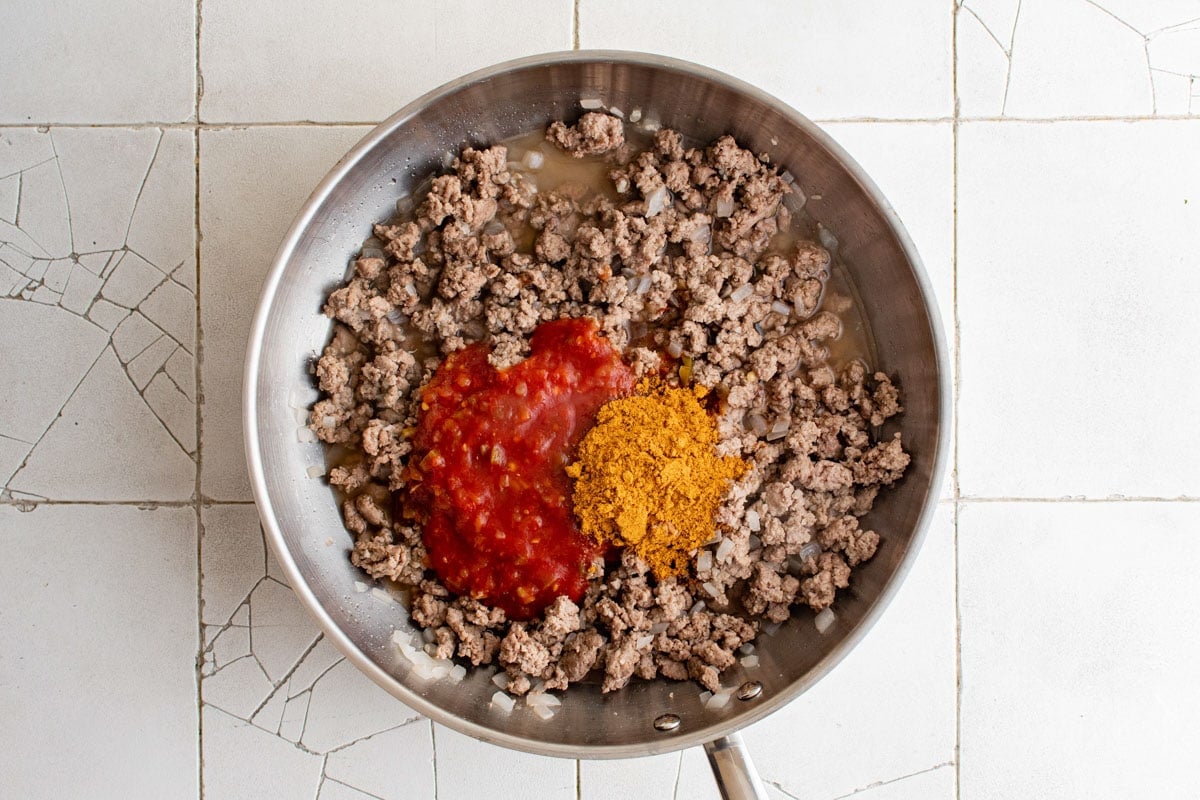 Cooked ground turkey ub a skillet with taco seasoning and salsa.