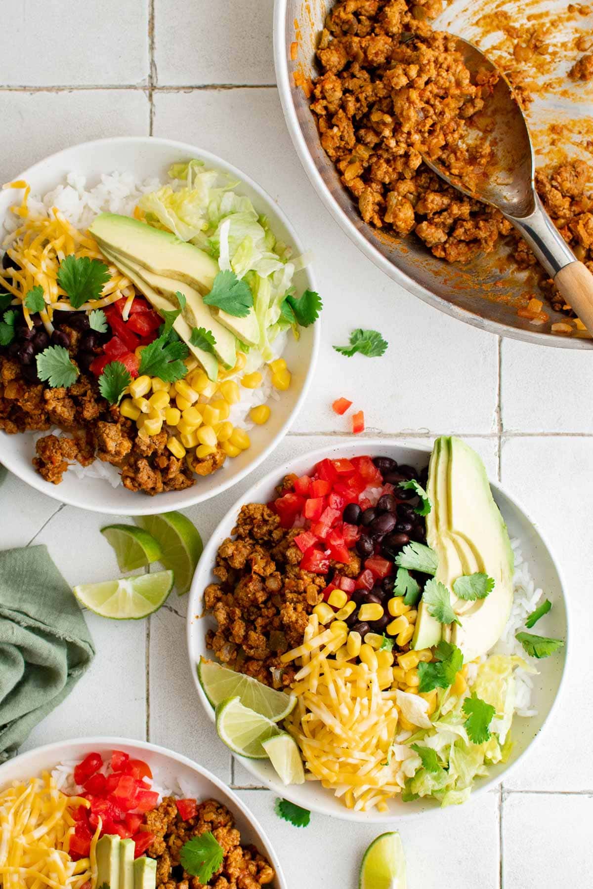 Turkey Taco Burrito Bowls are loaded with ground turkey taco meat, rice, black beans and a variety of toppings. This recipe will become a dinnertime staple! Turkey burrito bowls, and a skillet of taco meat.