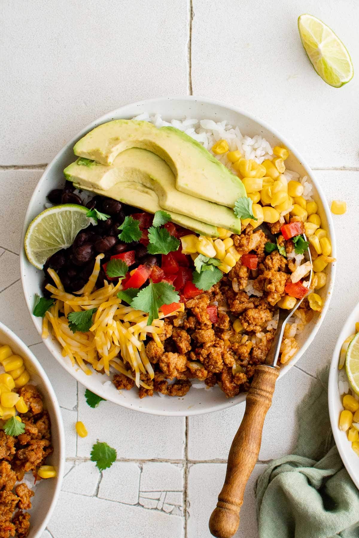 Turkey Taco Burrito Bowls are loaded with ground turkey taco meat, rice, black beans and a variety of toppings. This recipe will become a dinnertime staple! Taco Bowl with rice, beans, meat, lettuce, avocado and cheese.