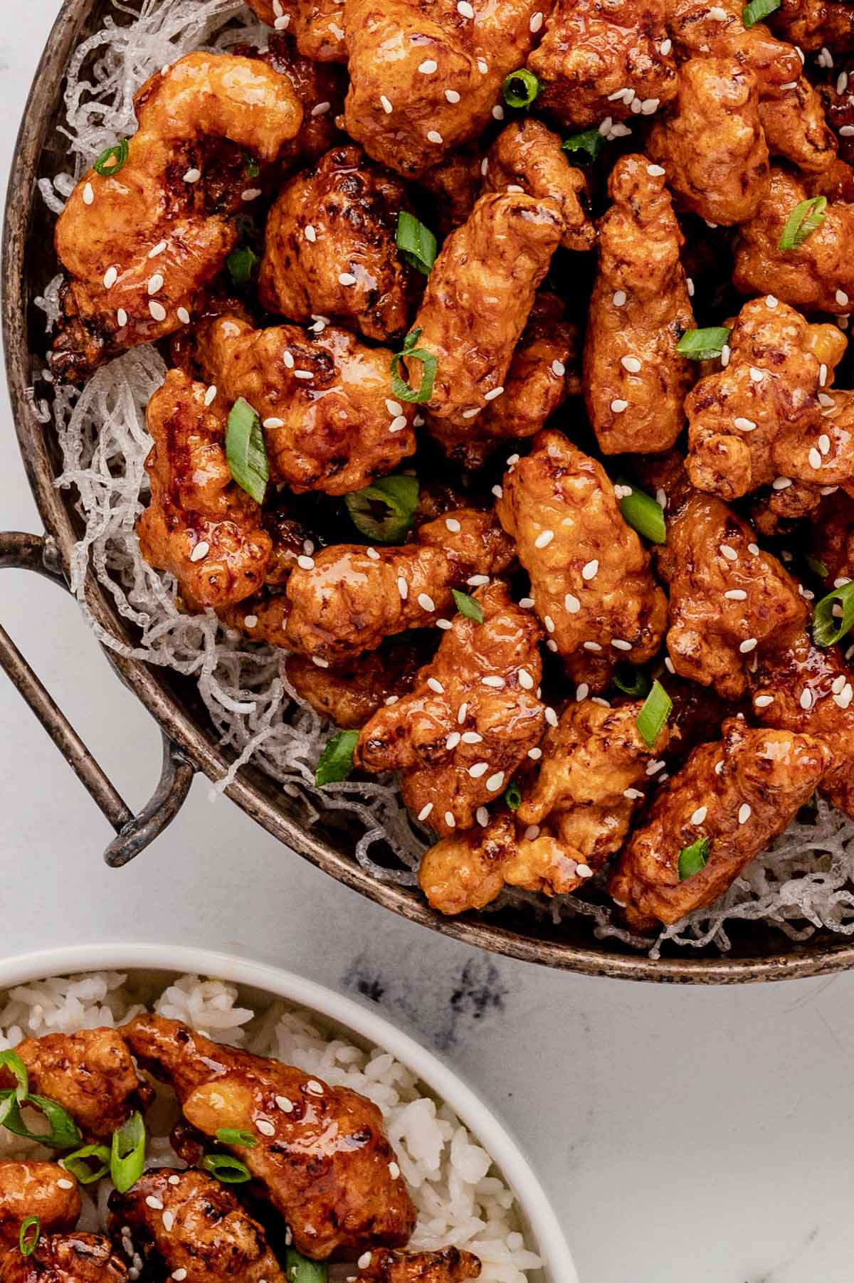 Large pan of crispy honey chicken over fried vermecelli noodles.