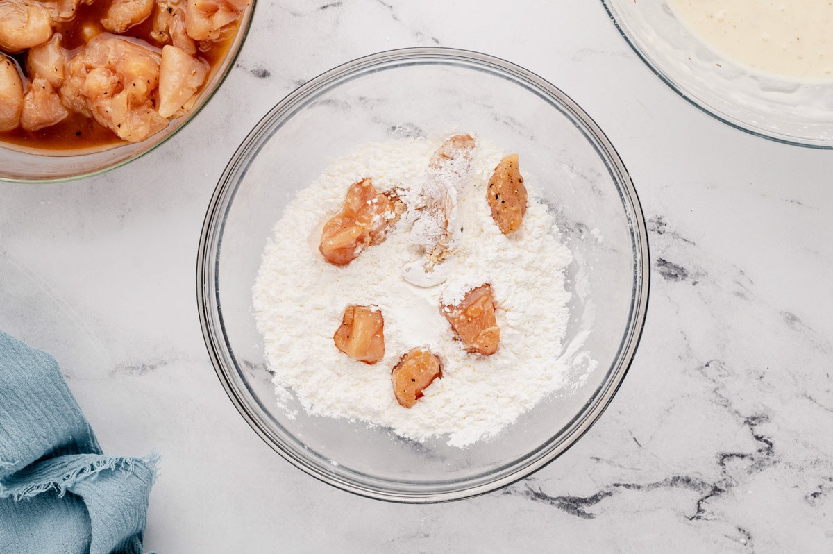 Chicken breast pieces in a dish of cornstarch.