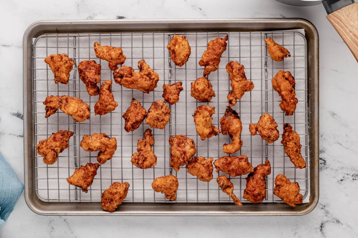 Fried chicken pieces on a wire rack.