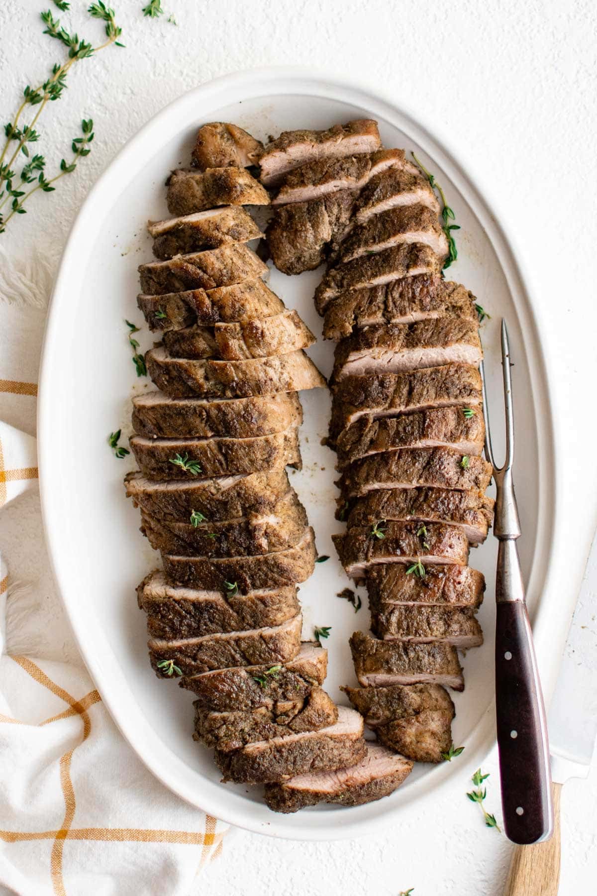 Sliced roasted pork tenderloin on a white platter. 