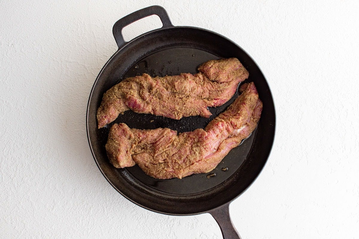 Two pork tenderloins in a cast iron skillet.