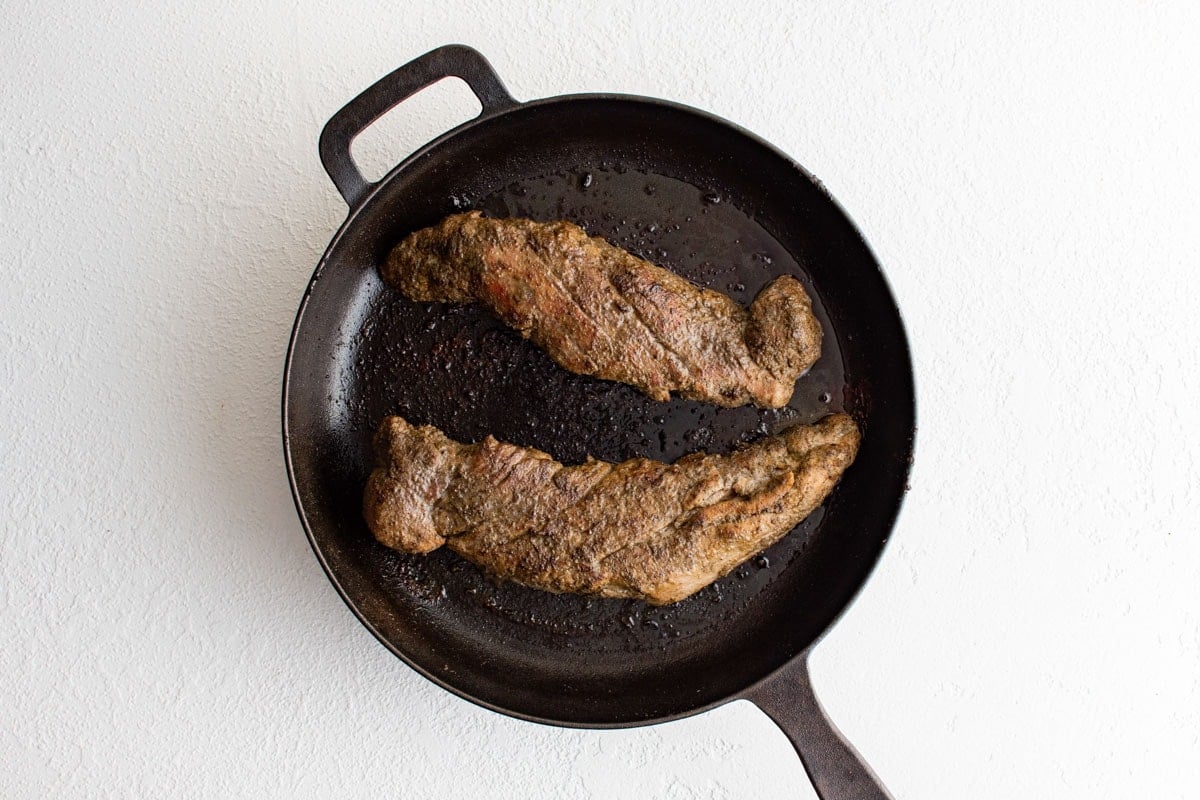 Seared and roasted pork tenderloins in a skillet.