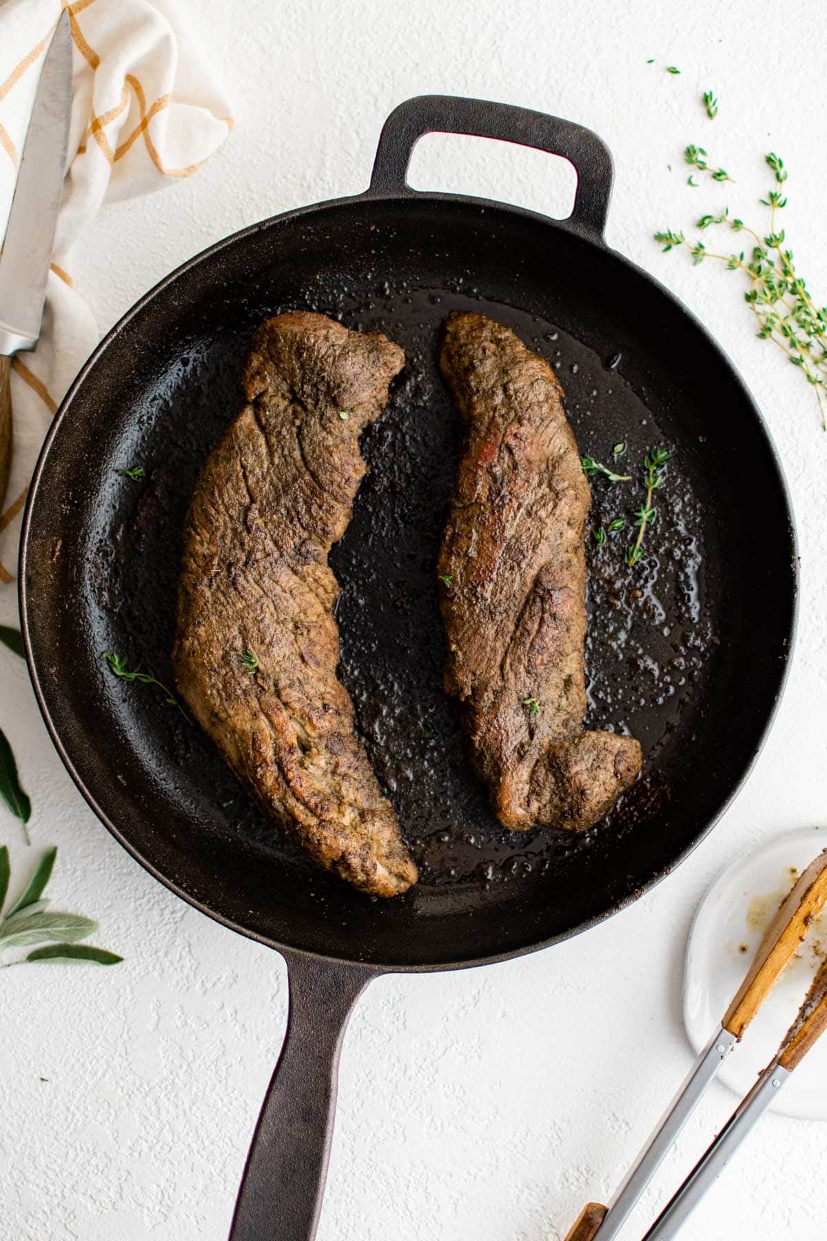 Cast iron skillet with 2 pork tenderloins.