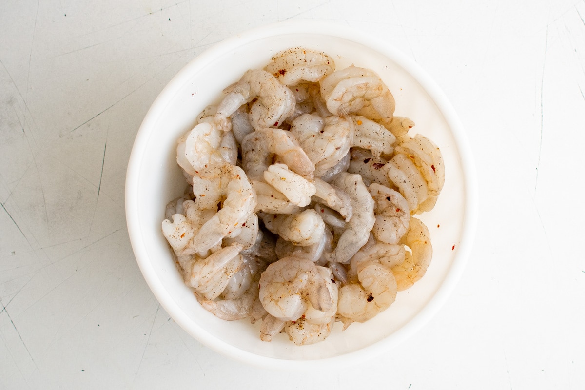 Raw shrimp in a white bowl.