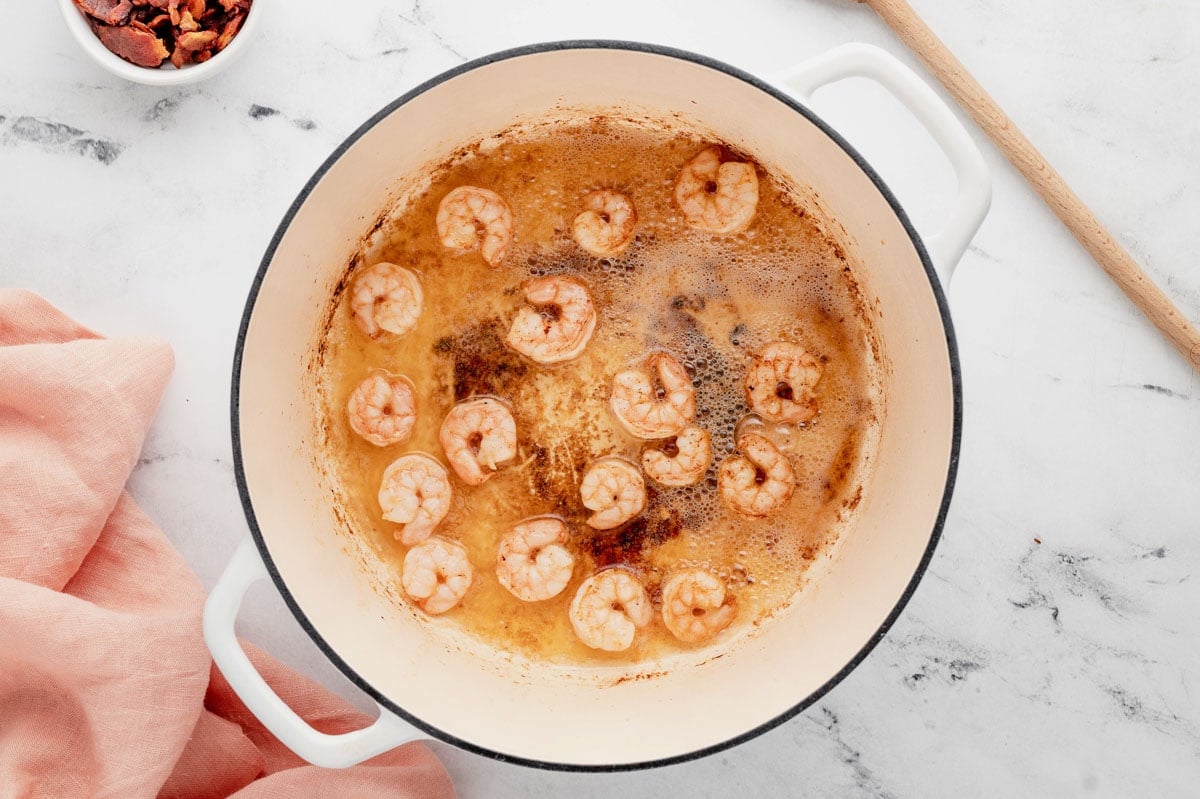 Shrimp and bacon cooking in a large pot.