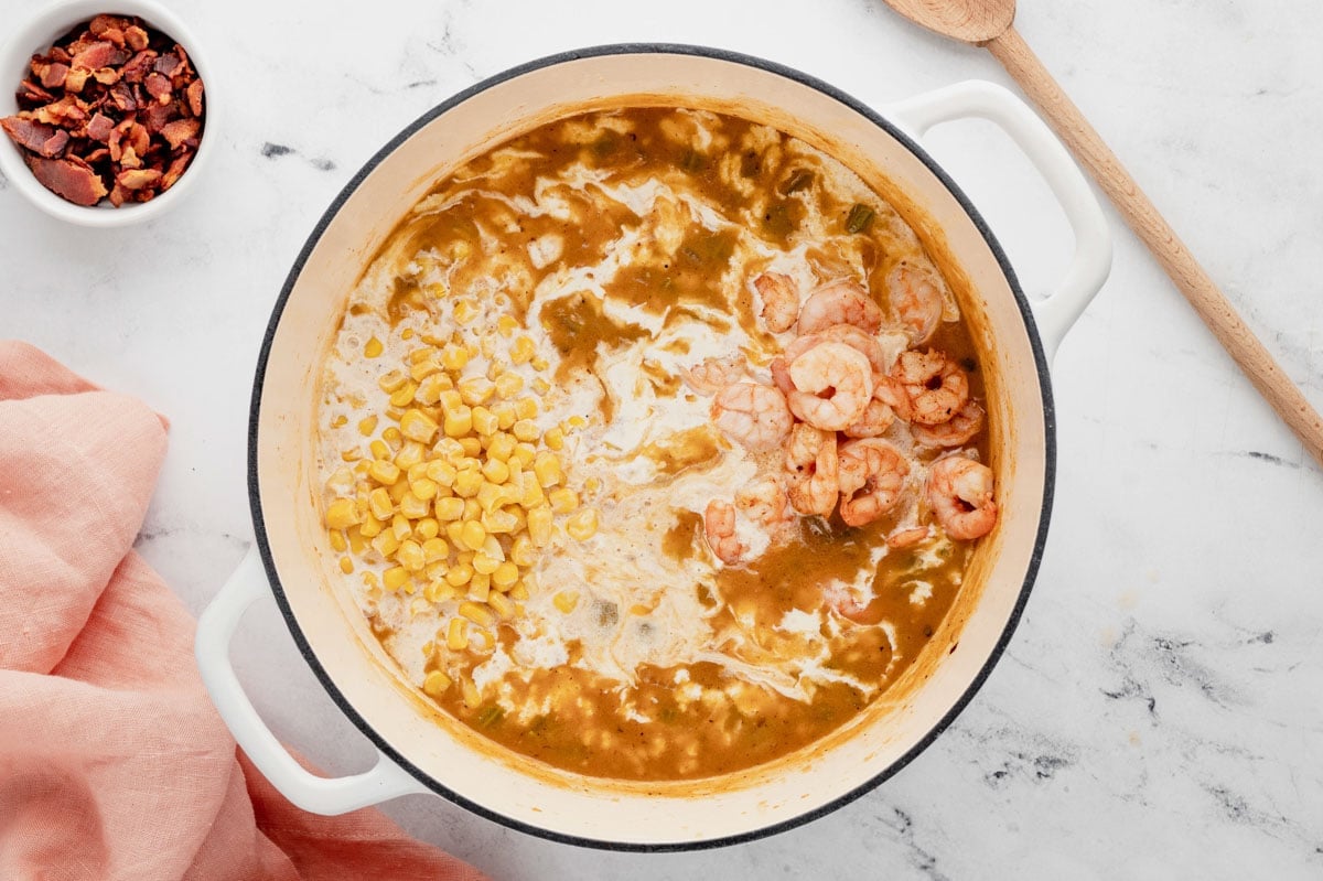 Broth and milk in a large pot with shrimp and corn.