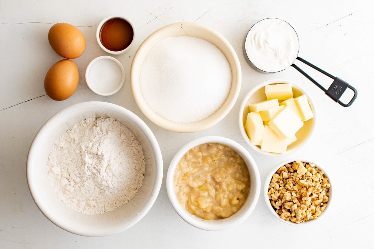 Ingredients for banana muffins - eggs, butter, sugar, flour, vanilla, walnuts, mashed bananas.