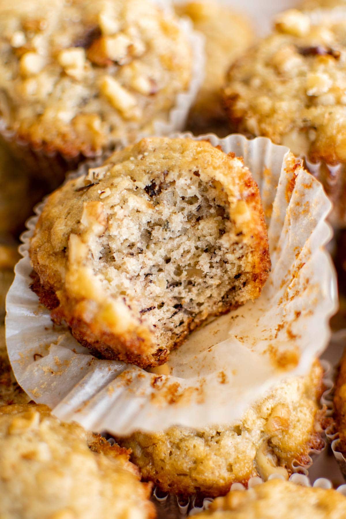 A banana muffin with the wrapper open and a bite taken out of it.