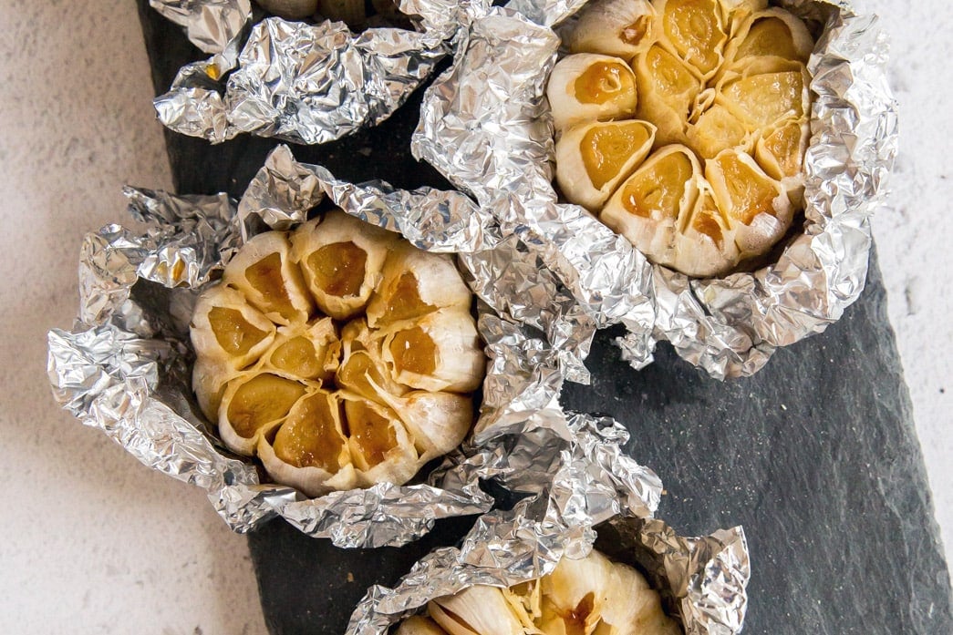 Roasted heads of garlic wrapped in foil.