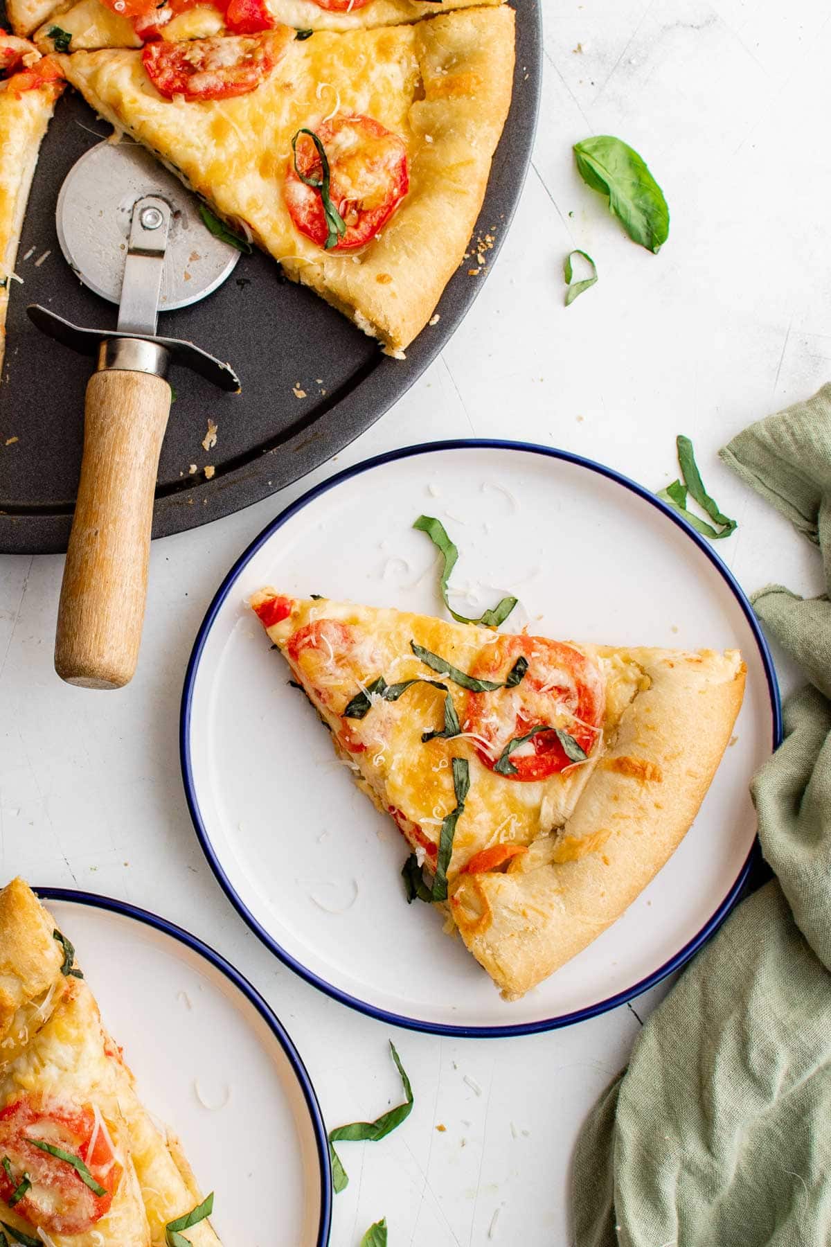 Pizza slices on plates, a pizza cutter. 