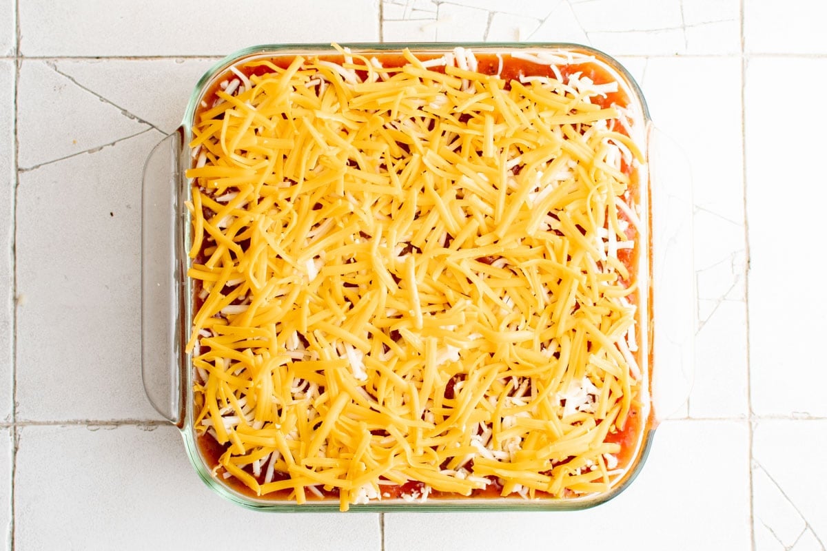 cheese on top of salsa in a baking dish.