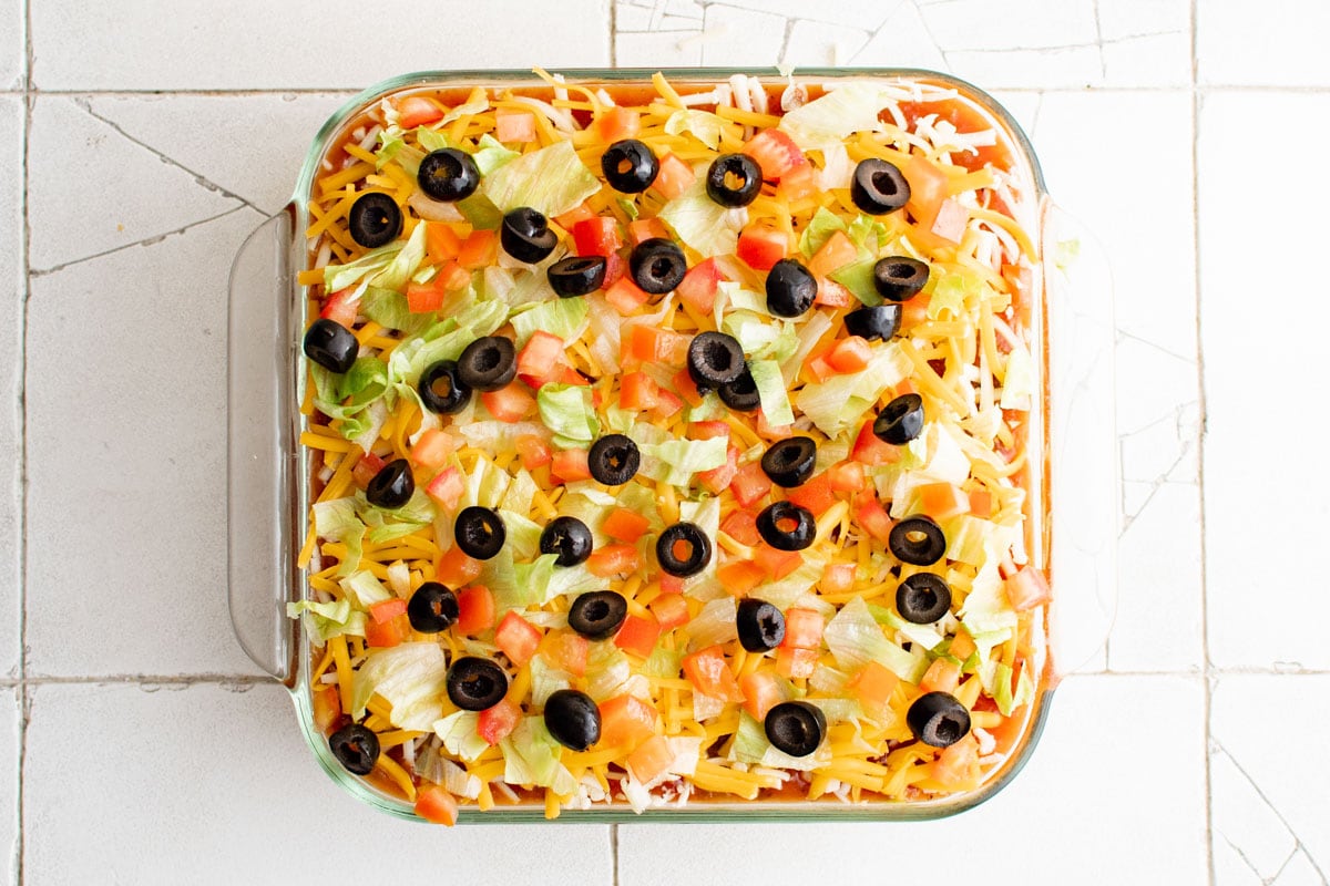 7 layer dip with lettuce olives and tomatoes on top.