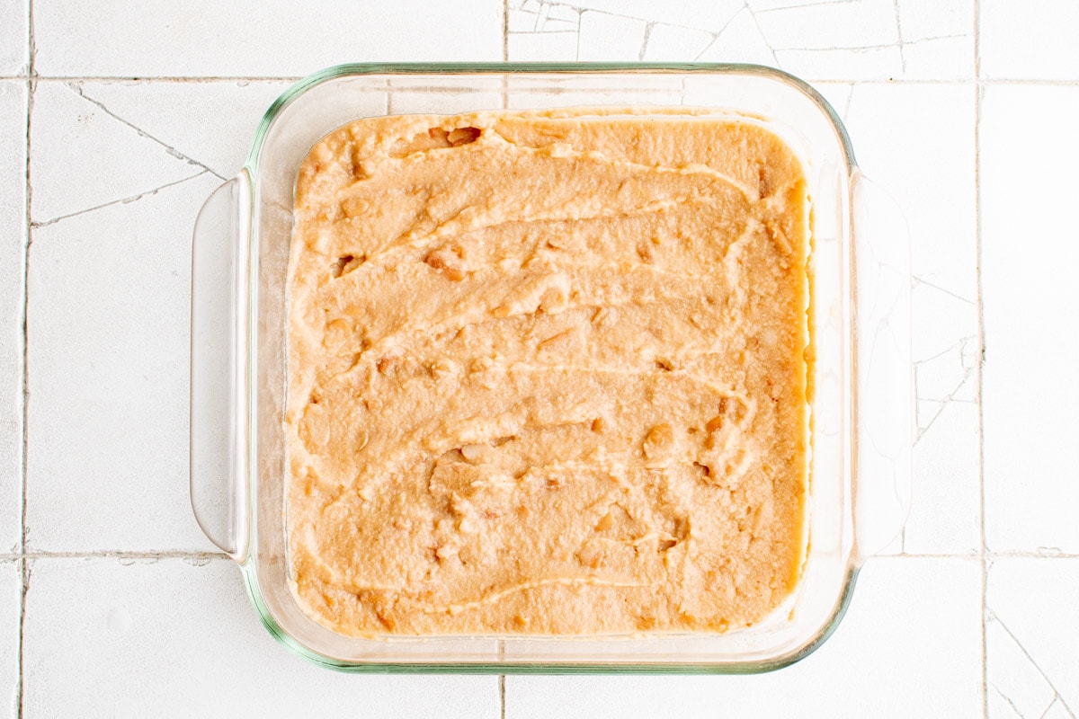 refried beans spread ij a square baking dish.