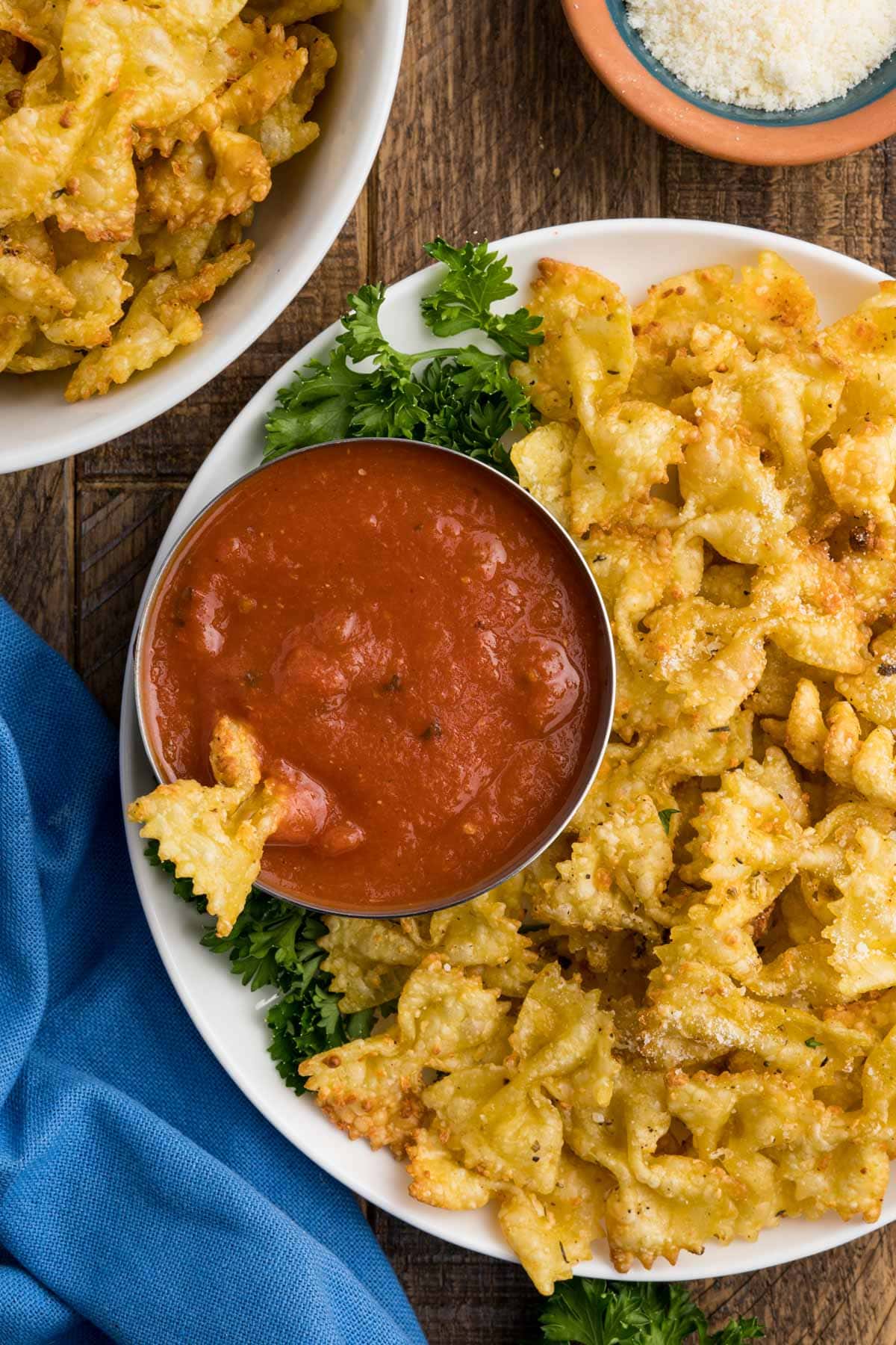 Crispy air fryer pasta chips on a white plate with a small dish of marinara.