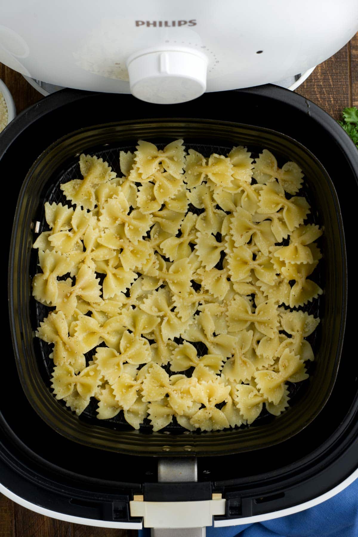 Cooked pasta in an air fryer basket.