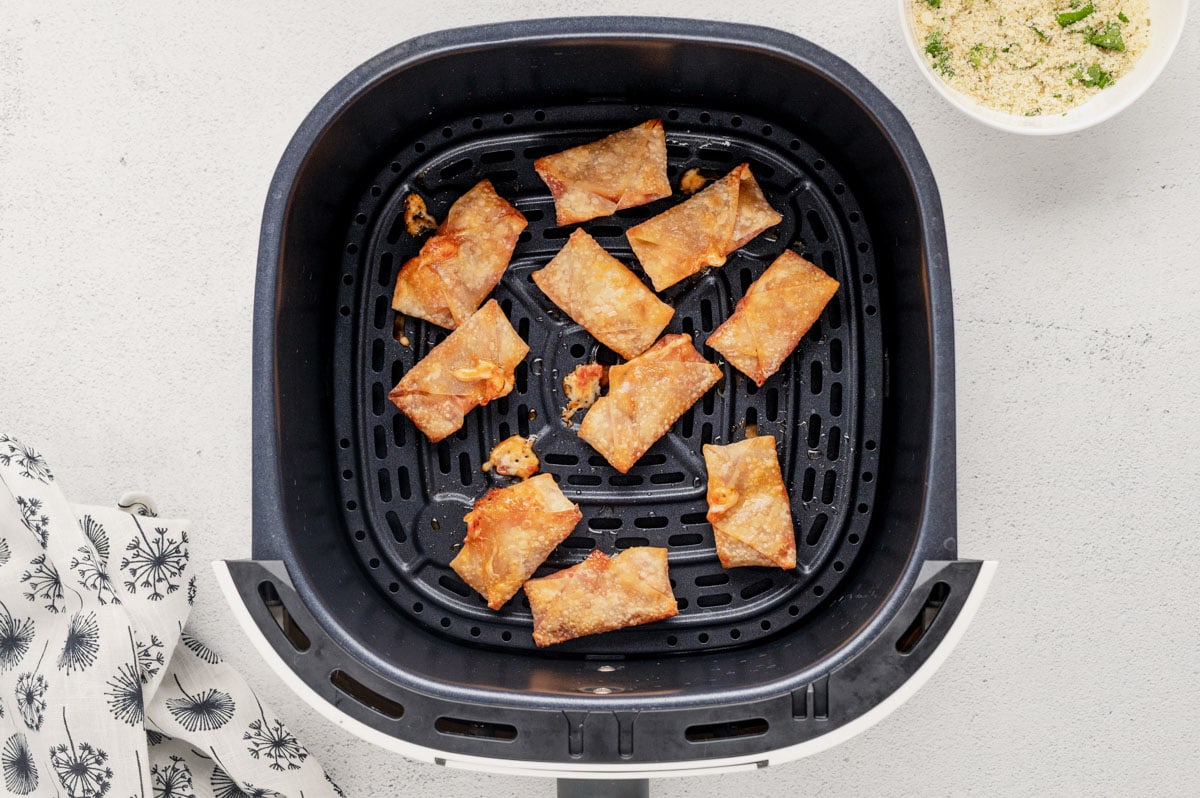 Cooked pizza rolls in an air fryer basket.