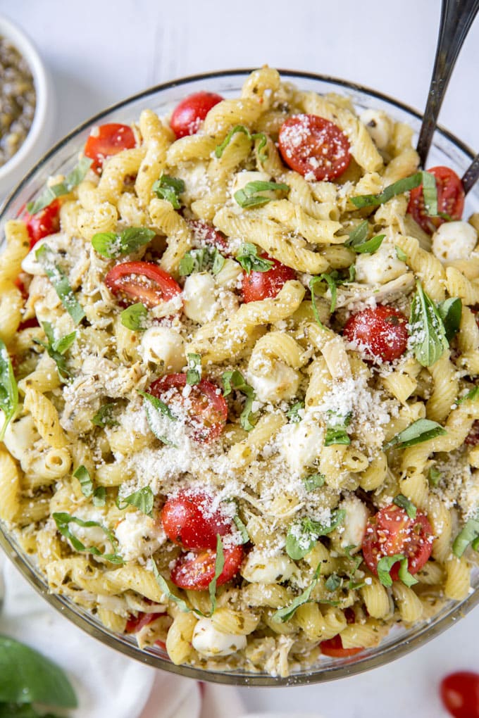 Chicken Pesto Pasta Salad in a large bowl, topped with parmesan cheese and with salad tongs.