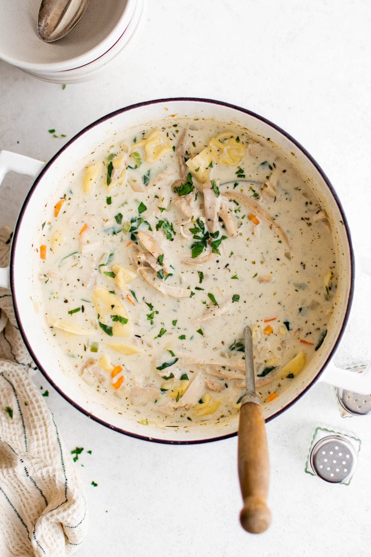 Pot of chicken tortellini soup with a ladle sticking out.