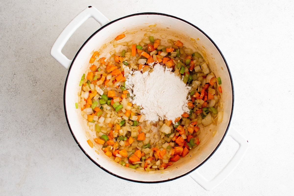 Flour added to sauteed carrots and celery in a dutch oven.