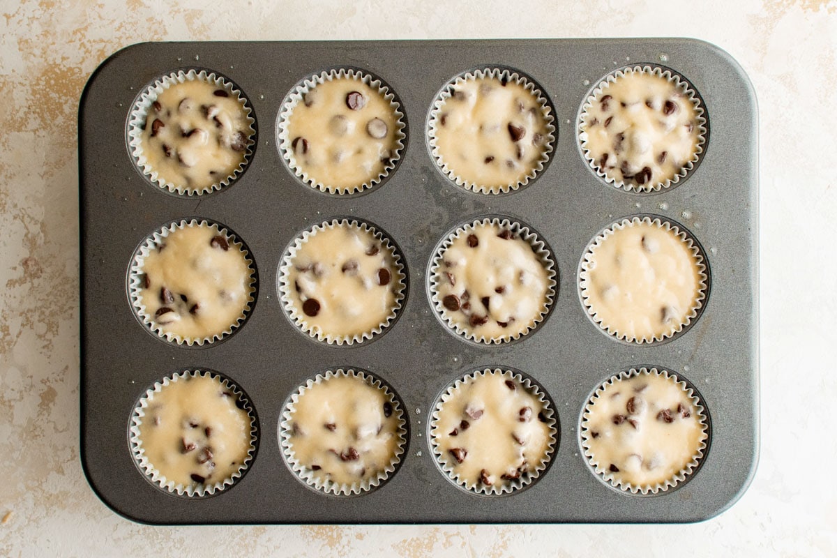 Chocolate chip muffin batter in a muffin pan.