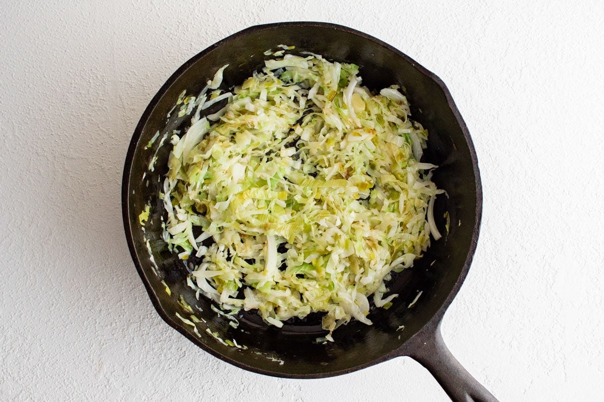 Shredded cabbage in a black skillet.