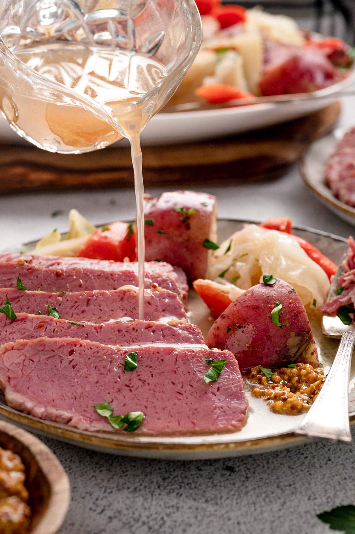 Juices from cooking being poured oven sliced corned beef.