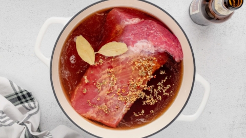 Corned beef, bay leaves and seasonings in a pot with broth and beer.