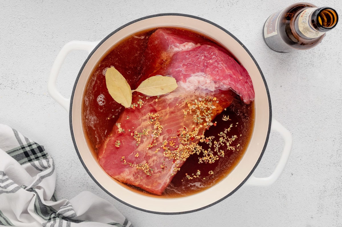 Corned beef, bay leaves and seasonings in a pot with broth and beer.