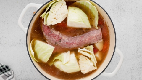 Corned beef in a pot of broth with cabbage.