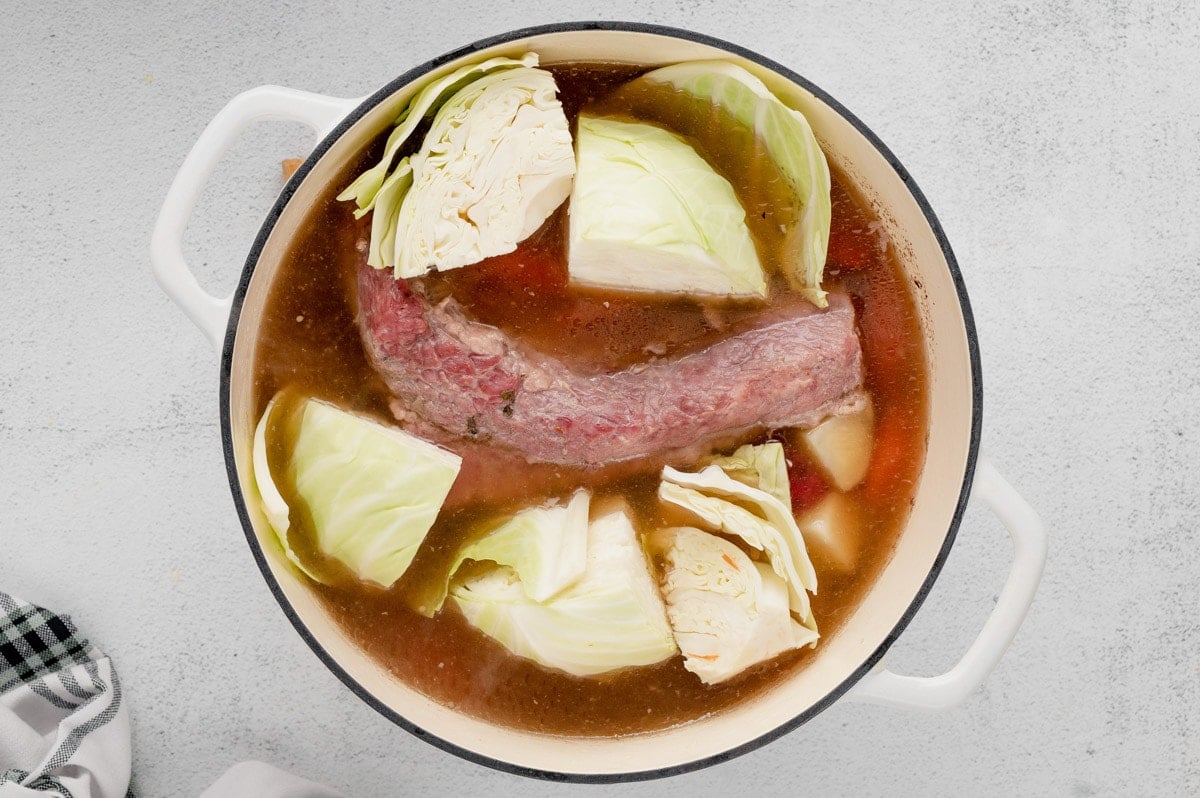 Corned beef in a pot of broth with cabbage.