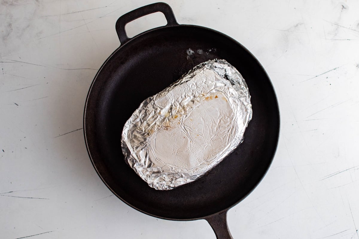 Foil wrapped sandwich in a skillet.